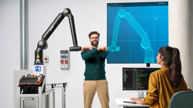 Dvaja spolupracovníci hrajú stolný futbal s asistenčným robotom Bosch Rexroth APAS.